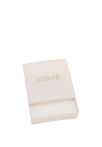 Liten beige rektangulär låda med ordet "amor" i guld på det delvis öppna locket mot en vit bakgrund.