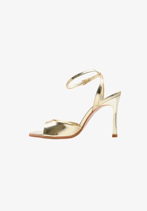 Sandalo metallizzato dorato con tacco alto, cinturino alla caviglia e punta aperta, dotato di un sottile tacco a spillo e chiusura con fibbia.