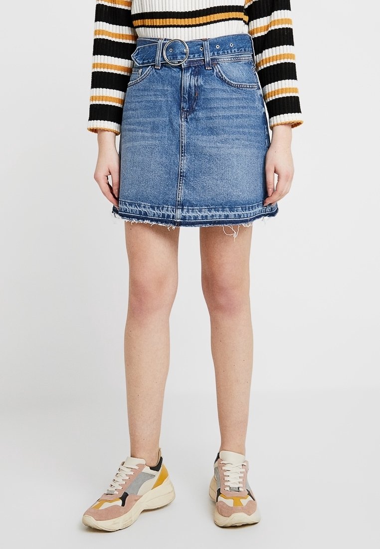 Džínová sukně s páskem, modrý praní, ořezané okraje a pět kapes. V kombinaci s vícebarevnými teniskami s robustní podešví.