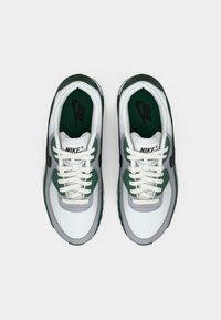 Nike Air Max sporta apavi ar baltu sietu augšdaļu, zaļiem akcentiem, pelēkiem dekoriem un baltām auklām. Melns Nike logo uz mēles.