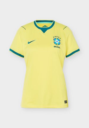Geltonas Brazilijos futbolo marškinėlis su žaliu apykaklės ir rankovių apvadu, Nike logotipu ant dešinės krūtinės ir Brazilijos herbu su penkiomis žvaigždėmis ant kairės krūtinės.