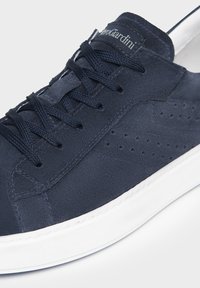 Sneaker in suede blu navy con suola in gomma bianca, caratterizzata da lacci piatti e piccole perforazioni sui lati. Etichetta del marchio sulla linguetta.