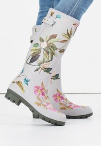 Botas de goma de lluvia con estampado floral en gris, con suelas y detalles en verde. Presentan flores rosas y azules con hojas detalladas.