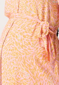 Pink dress with gold abstract pattern, featuring a tied belt at the waist, smooth fabric texture, and button closure detail.