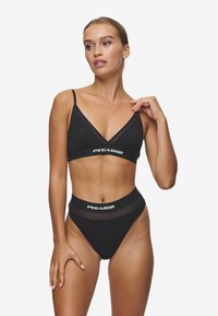 Čierny bralet a bikiny s vysokým pásom, ktoré majú tenké ramienka a kontrastný pás "PEGADOR". Hladká látka a minimalistický dizajn.