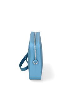 Borsa di colore blu chiaro, con zip e profilo sottile, dotata di tracolla, posizionata in verticale su uno sfondo bianco.
