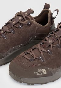 Кафяви велурени туристически обувки с брандрани връзки и лого "The North Face" отстрани, с петнеста междинна подметка и ленти за дърпане на петата.