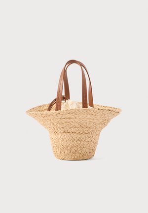 Pītā salmu soma ar platu, izplešamu atvērumu un diviem brūniem ādas rokturiem uz vienkārša fona.