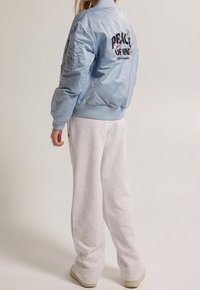 Bomber jacket blu chiaro con polsini e orlo a coste, caratterizzato da ricamo "PEACE OF MIND" e dettagli a margherita. Abbinato a pantaloni della tuta grigi.
