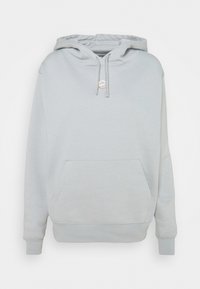 Ljusgrå luvtröja gjord av mjukt tyg. Har en känguruficka, luva med dragsko och ribbade muddar. Enkel design utan mönster.