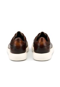 Braune Ledersneaker mit glatter Oberfläche, gekennzeichnet durch ein am Fersenbereich geprägtes Logo und einer weißen Gummisohle mit minimaler Gestaltung.