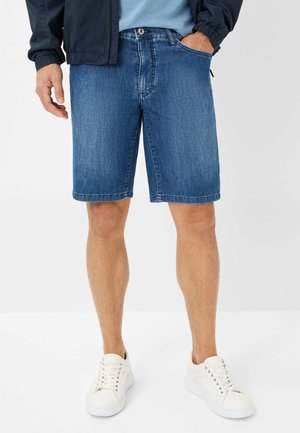 Shorts en denim de bleu moyen, avec une coupe slim, un design à cinq poches et des coutures contrastantes. Associés à des baskets blanches et une chemise bleu clair.