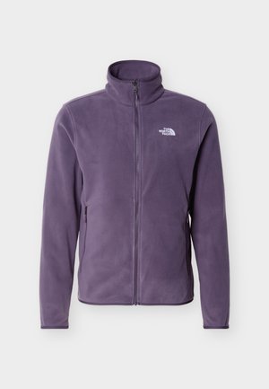 Lila, cipzáros polárdzseki álló gallérral, oldalsó cipzáras zsebekkel és fehér "The North Face" logóval a bal mellrészen.