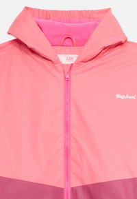 Rosa Windjacke mit Kapuze, mit einem Reißverschluss vorne, elastischem Kragen und einem kontrastierenden dunkelrosa unteren Abschnitt. "Playshoes"-Logo in Weiß.