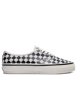 Zwart-witte geruite low-top Vans sneaker met witte veters en dikke witte zool, zijaanzicht.