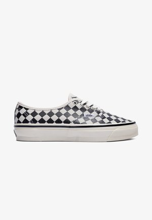Zwart-witte geruite low-top Vans sneaker met witte veters en dikke witte zool, zijaanzicht.
