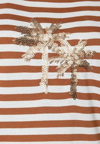 Braun-weiß gestreiftes Oberteil mit einem Palmenmotiv aus glänzenden goldenen Pailletten, das dem Stoff Textur und visuelle Details verleiht.