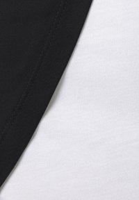 Black cotton fabric overlapping white cotton fabric, showing smooth texture and contrast between colors. Neat stitching along the edges.