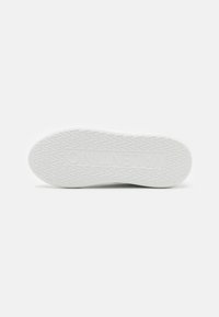 Hvit sneakersåle med et teksturert mønster og fremtredende merkevare. Flat design og slitesterkt materiale med trekantede trainelementer.