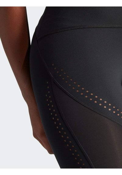Zwarte sportleggingen met een matte afwerking, ademende meshpanelen met perforaties, en platte naden voor extra comfort.