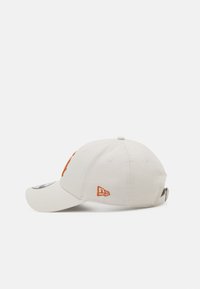 Weiße Kappe mit einem orangefarbenen Sticklogo auf der Vorderseite. Verfügt über einen gebogenen Schirm und einen verstellbaren Riemen auf der Rückseite. Texturiertes Baumwollmaterial.