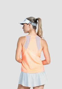 Sportieve tanktop in feloranje met mesh inzetstukken, gecombineerd met een witte rok met kleine zwarte stippen. Witte zonnevisor inbegrepen.