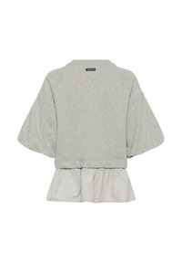 Gaiši pelēks īss krekls ar plašām īsām piedurknēm un baltu krokotu auduma slāni, kas redzams no apakšas aizmugurē.