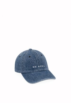 Casquette de baseball en denim bleu avec texte blanc "OH APRIL" à l'avant, design six panneaux et œillets de ventilation noirs.