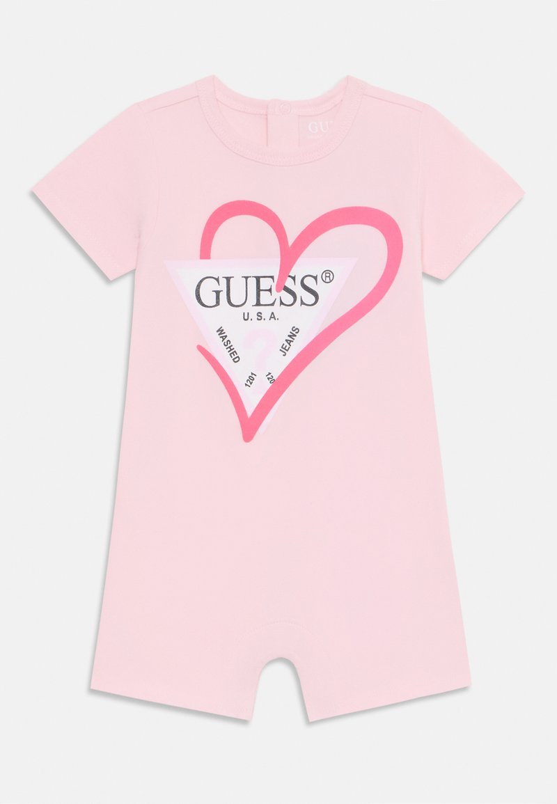 Růžový overal s krátkým rukávem vyrobený z měkké bavlny, s velkým srdcovým grafikou a logem "GUESS" v černé a růžové barvě.