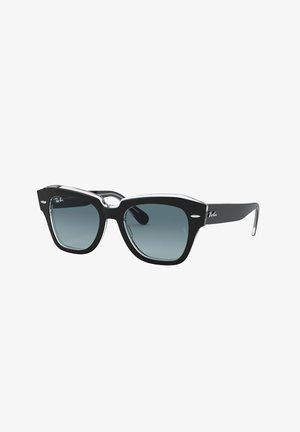 Occhiali da sole neri in plastica con lenti quadrate oversize, dotati di una montatura trasparente, lenti sfumate e un sottile logo Ray-Ban sulla tempia.