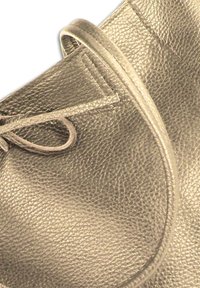 Sac à main en cuir gris foncé avec une surface texturée, une forme arrondie et un détail de sangle nouée. Présente un design lisse et minimaliste.
