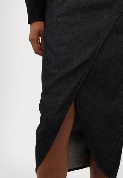 Fustă din denim negru cu un design înfășurat diagonal și o fanta înalte pe coapsă, având o textură netedă și detalii de cusătură curate.