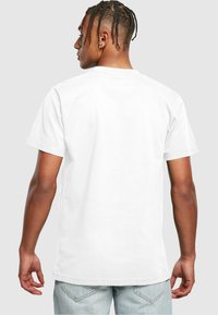 Hvid bomulds T-shirt med korte ærmer, rund halsudskæring og lige kant. Glat tekstur, minimalistisk design, ingen synlige logoer eller mønstre.