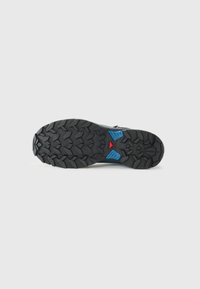 Sola de sapatilha atlética preta com padrão texturizado, apresentando detalhes em azul e vermelho. Material de borracha durável projetado para tração.