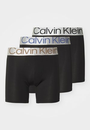 Trois paires de boxers noirs avec des ceintures élastiques. Chaque ceinture présente le logo "Calvin Klein" dans des couleurs différentes : argenté, bleu et marron.