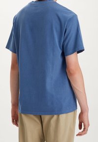 T-shirt en coton bleu avec un col rond et des manches courtes, présentant une texture douce et une coupe décontractée, vu de dos.