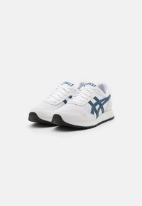 Pair of white and navy blue Asics sneakers with laces, mesh and suede panels, and black rubber soles on a plain white background.