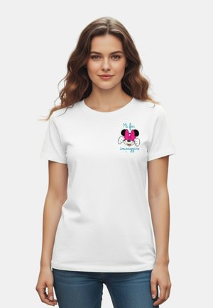 Donna con lunghi capelli mossi che indossa una maglietta bianca con Minnie Mouse in versione cartone animato e testo in italiano sul lato sinistro del petto, abbinata a jeans blu.