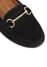 Black suede loafer featuring a gold-tone hardware accent, stitched details, and a textured insole. No visible heel; sleek, streamlined design.