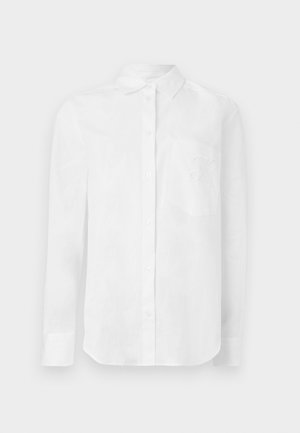 Chemise à manches longues blanche avec boutons, col et poche poitrine avant, ornée d'un motif brodé discret.