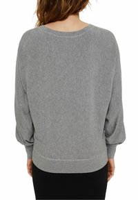 Pull en maille grise à coupe décontractée, encolure large et manches ballon. Poignets et ourlet côtelés apportent de la texture. Matière douce et légère.