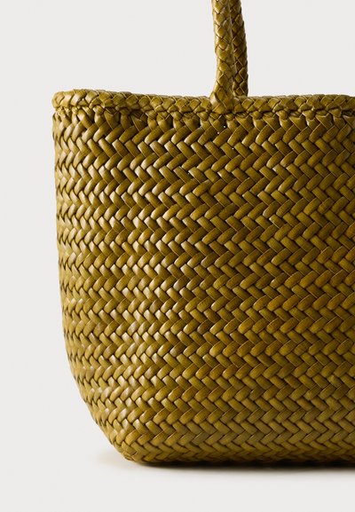 Κοντινή λήψη υφαντού καλάθι σε ελιά πρασινίζουσα απόχρωση με πλεκτή υφή και μια λαβή σε απλό φόντο.