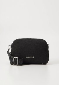 Black denim crossbody bag with a silver zipper, featuring a logo and an adjustable black strap with a bold printed detail.