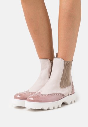 Botas de cuero hasta el tobillo con una combinación de colores en rosa claro y beige, que presentan una punta redondeada, paneles laterales elásticos y una suela blanca gruesa.
