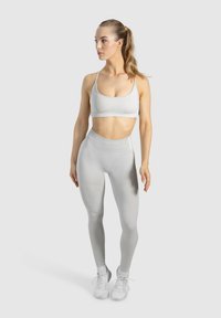 Hellgraues Sportset mit einem figurbetonten Sport-BH und hochgeschnittenen Leggings, die eine glatte Textur und minimale Nähte aufweisen.