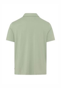 Grünes Polohemd mit klassischem Kragen, kurzen Ärmeln und glatter Textur, entworfen in einem lässigen Schnitt mit geradem Saum.