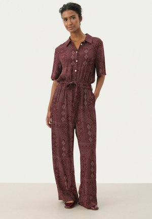 Burgundy jumpsuit with short sleeves, button-up front, waist tie, and geometric patterns in contrasting colors; wide-leg design.