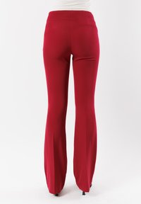 Pantaloni rossi a zampa d'elefante in tessuto liscio ed elasticizzato. Design a vita alta con un retro pulito senza tasche visibili o decorazioni.