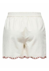 Shorts en lin blanc avec un ourlet festonné et des détails de broderie rouge. Dispose d'une taille élastique pour le confort et la facilité de port.