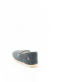 Chausson en feutre gris avec un bout rond, une surface douce et texturée, une couture contrastante en noir et blanc, et une semelle en caoutchouc de couleur claire.